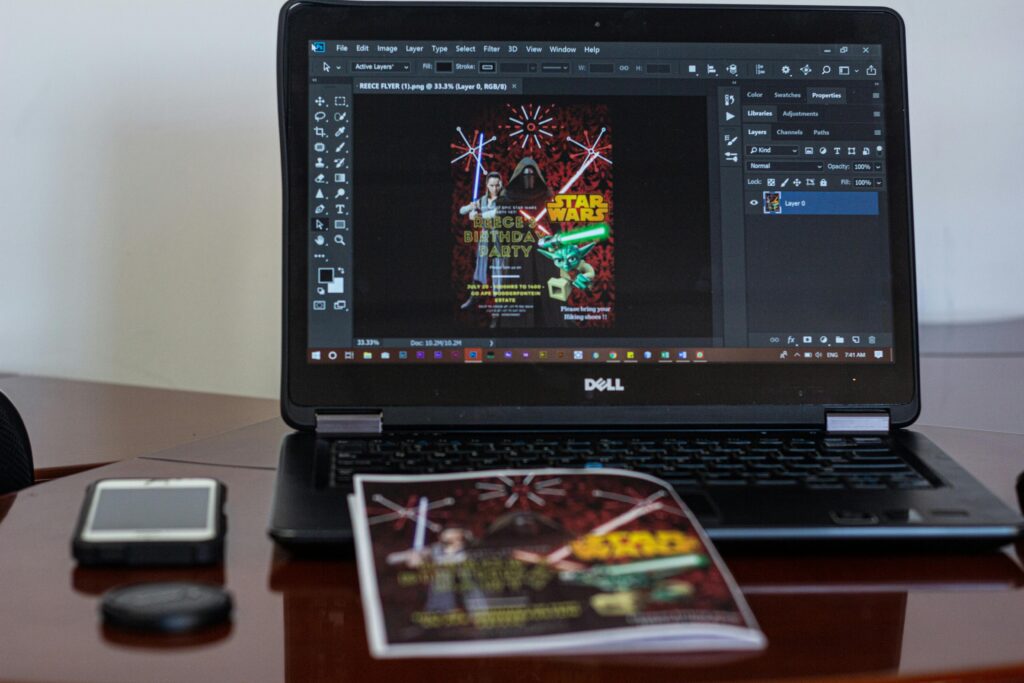 A laptop displaying Star Wars party invitation design in a workspace setting.